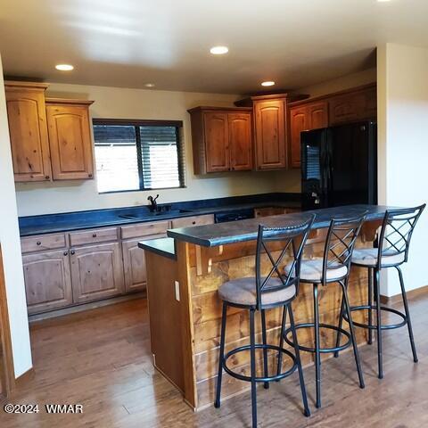 kitchen with a kitchen breakfast bar, dark countertops, freestanding refrigerator, and a center island