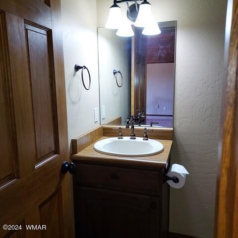 half bath featuring a textured wall and vanity