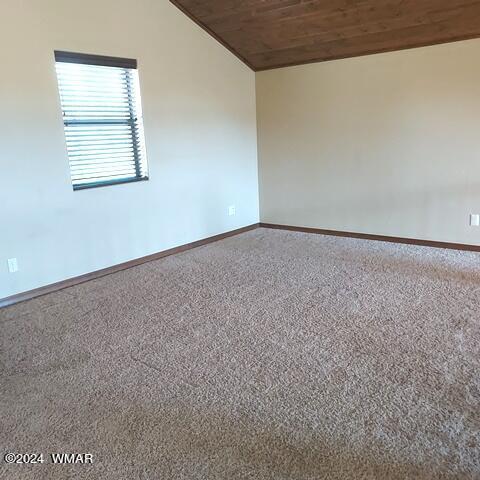 carpeted empty room with vaulted ceiling, wooden ceiling, and baseboards