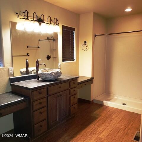 full bathroom featuring a shower, wood finished floors, and vanity