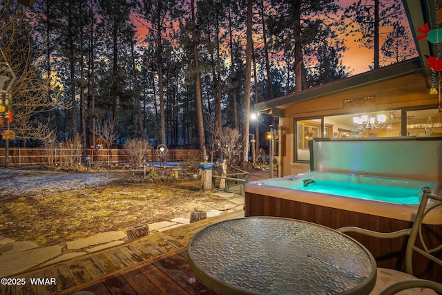 exterior space featuring outdoor dining space, a trampoline, fence, and a hot tub