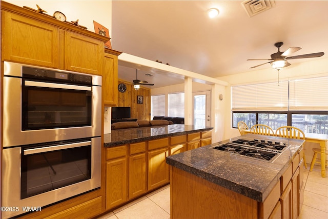 7125 Elk Trl, Show Low, AZ 85901 - kitchen with stainless steel double oven, ceiling fan, stovetop with downdraft, light tile patterned flooring, and brown cabinetry