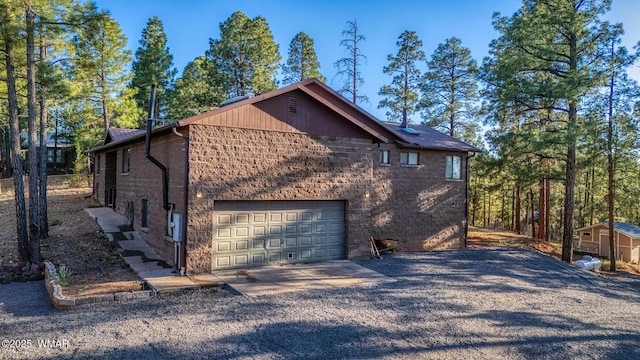 7125 Elk Trl, Show Low, AZ 85901 - view of home's exterior with driveway, an attached garage, a storage unit, and brick siding