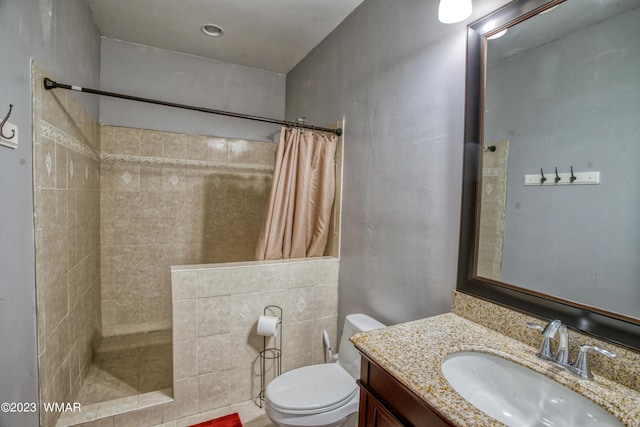 full bathroom with a tile shower, toilet, and vanity