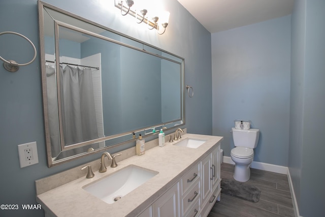 bathroom featuring wood finished floors, toilet, baseboards, and double vanity