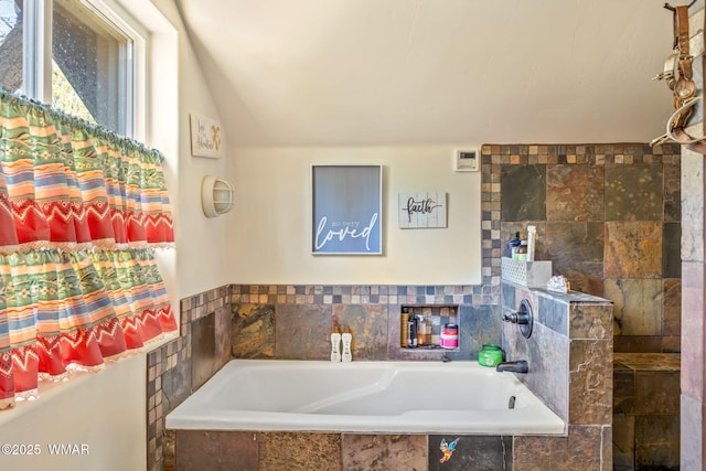 bathroom featuring vaulted ceiling and a garden tub