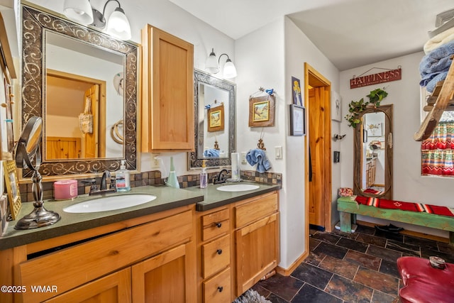 bathroom with stone finish flooring, a sink, baseboards, and double vanity