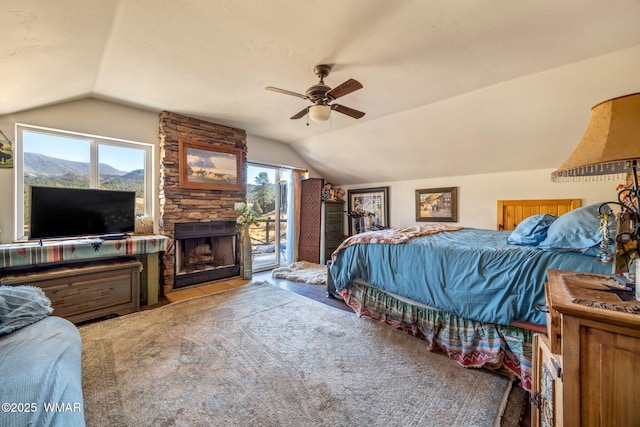 bedroom featuring access to exterior, vaulted ceiling, a stone fireplace, and ceiling fan