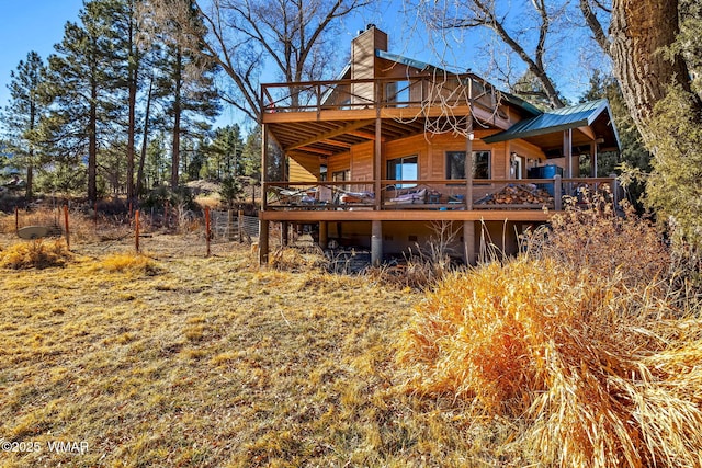 rear view of house featuring metal roof, a chimney, and a wooden deck