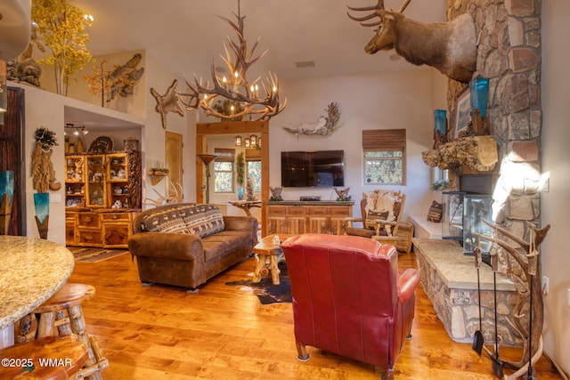 living area featuring visible vents, a fireplace, light wood-style flooring, and an inviting chandelier