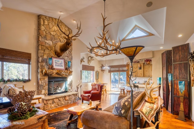 living room featuring a stone fireplace, light wood-style floors, high vaulted ceiling, a notable chandelier, and recessed lighting