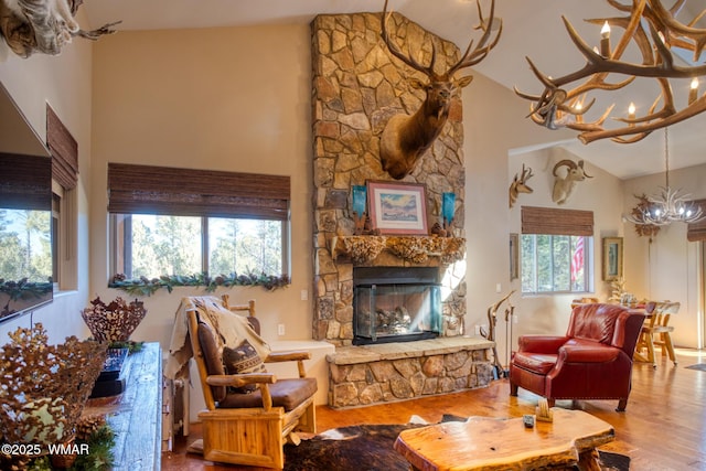 living room with a chandelier, a fireplace, high vaulted ceiling, and wood finished floors