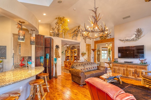 living room featuring visible vents, a towering ceiling, light wood-style flooring, an inviting chandelier, and recessed lighting