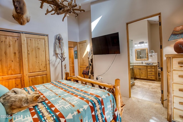 bedroom with an inviting chandelier, ensuite bath, a high ceiling, and light colored carpet