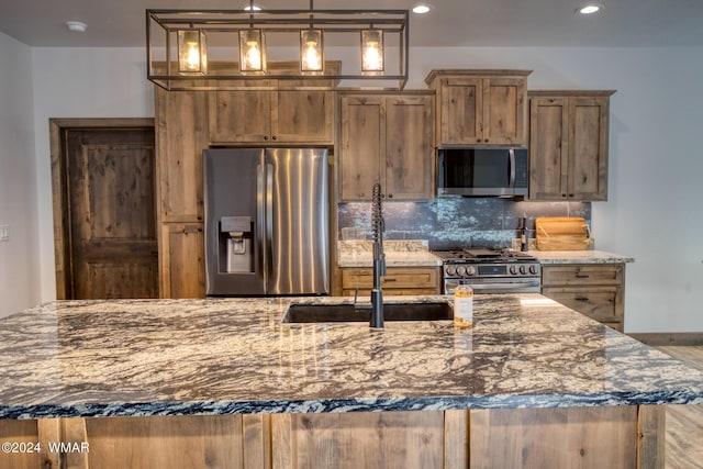 kitchen featuring appliances with stainless steel finishes, backsplash, light stone counters, decorative light fixtures, and a sink