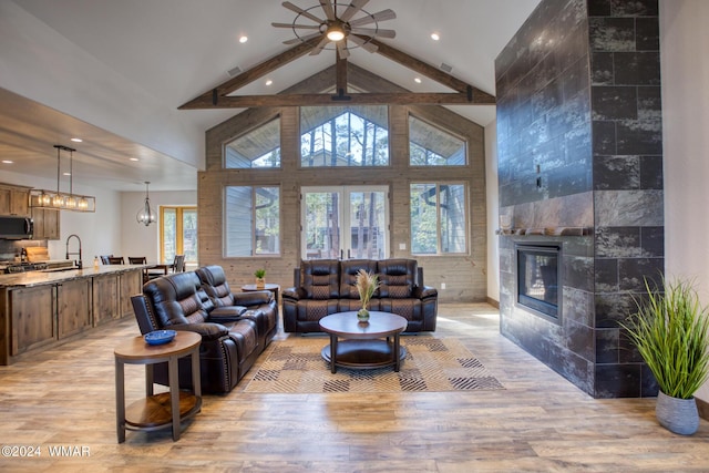 living area with high vaulted ceiling, light wood finished floors, beamed ceiling, and a fireplace