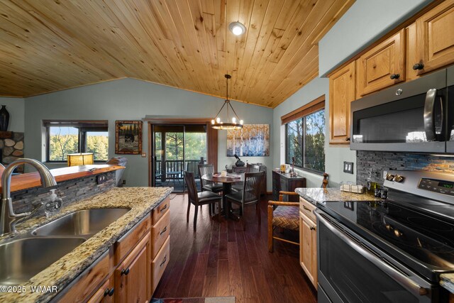 kitchen featuring brown cabinetry, light stone counters, decorative light fixtures, stainless steel appliances, and a sink