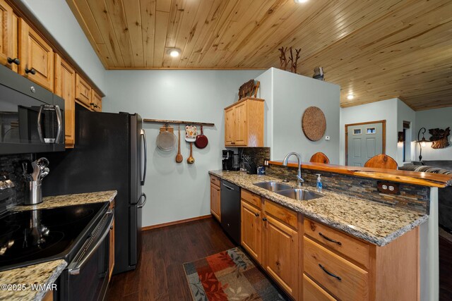 kitchen with a peninsula, black appliances, dark wood finished floors, and a sink