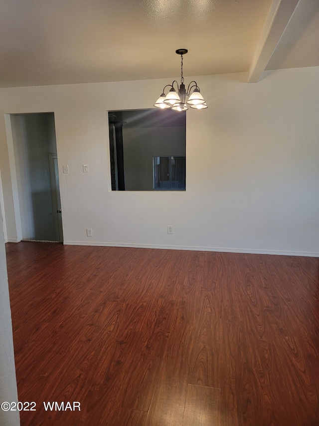 empty room featuring baseboards, wood finished floors, and an inviting chandelier