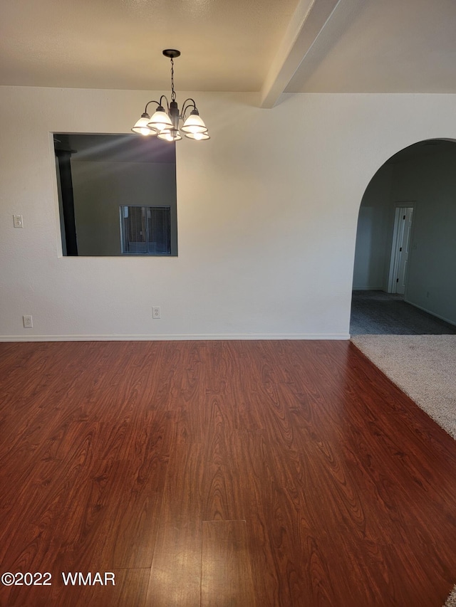 empty room featuring arched walkways, beamed ceiling, wood finished floors, and a notable chandelier