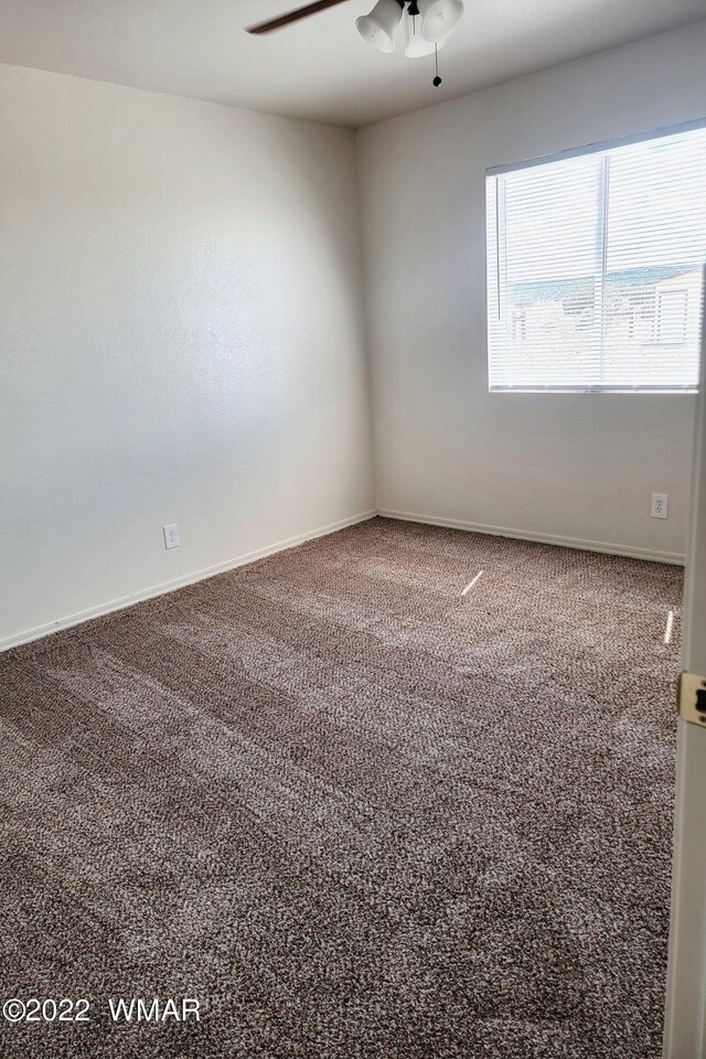 carpeted empty room with baseboards and a ceiling fan