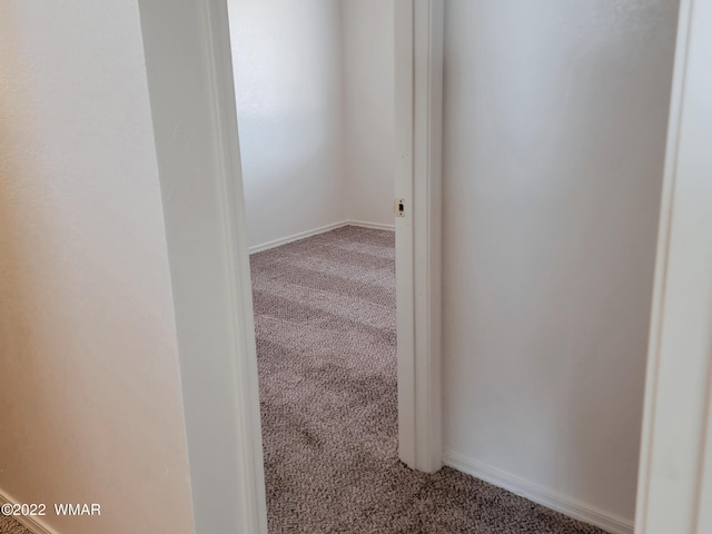 hallway featuring carpet floors and baseboards