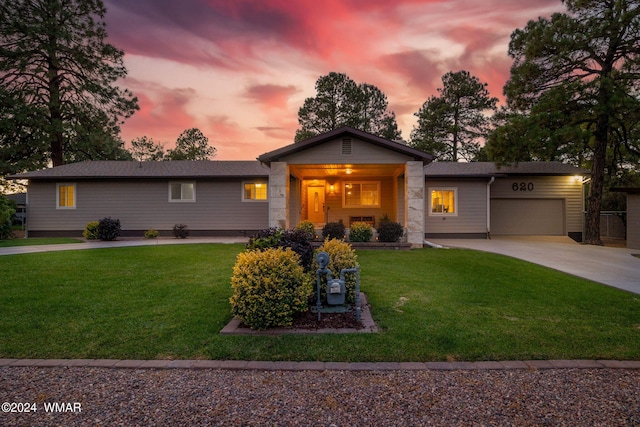 single story home with driveway, an attached garage, and a yard