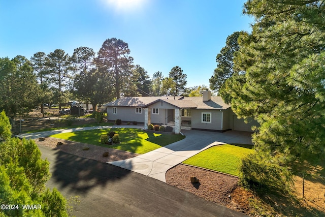 view of front of property featuring a chimney, concrete driveway, and a front yard