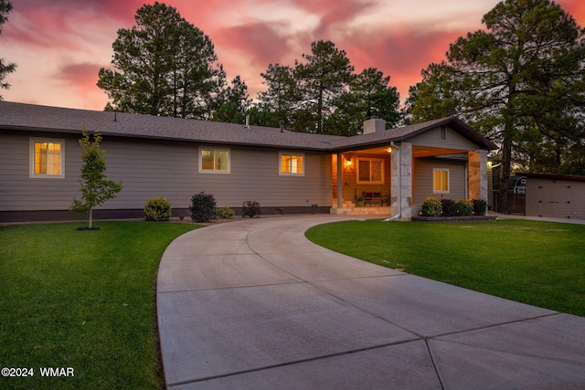 single story home with driveway, a chimney, and a lawn