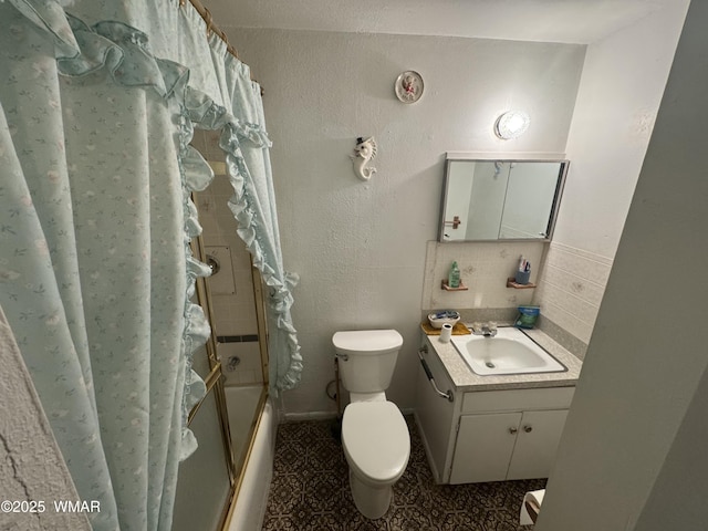 bathroom featuring shower / bath combination with glass door, vanity, toilet, and decorative backsplash