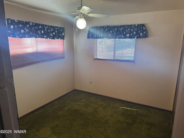 spare room featuring a ceiling fan, dark colored carpet, and baseboards