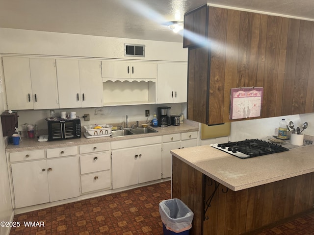 kitchen featuring gas cooktop, a sink, visible vents, white cabinets, and light countertops