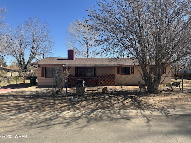 single story home featuring driveway, a fenced front yard, and a chimney