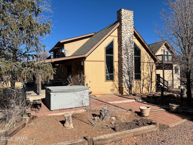 view of side of home featuring crawl space, a balcony, a hot tub, and a chimney