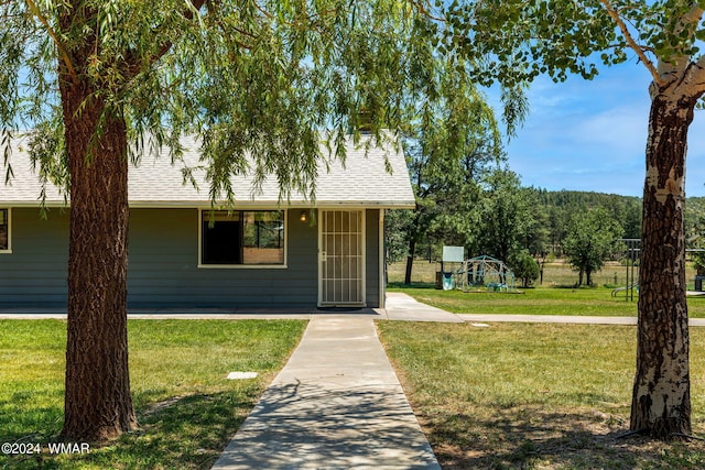 view of front of property featuring a front lawn and roof with shingles