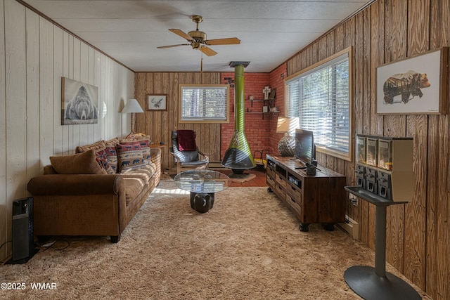 living area with ceiling fan, a wood stove, carpet flooring, and a wealth of natural light