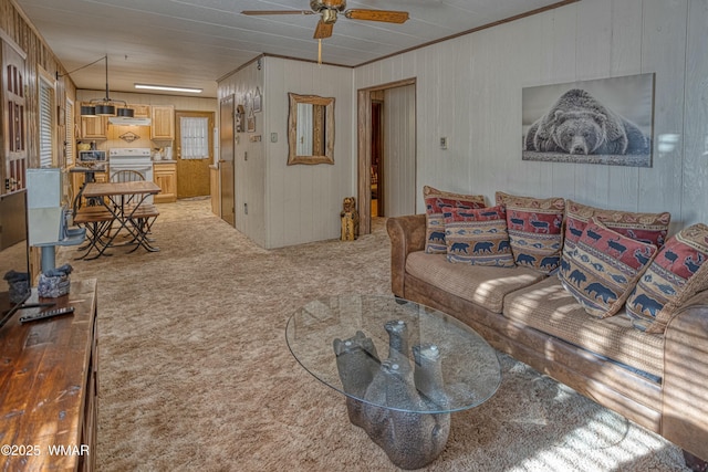 living room with ornamental molding, carpet flooring, and a ceiling fan