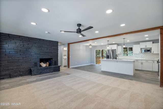 261 S 5th Pl, Show Low, AZ 85901 - unfurnished living room with recessed lighting, ceiling fan, a stone fireplace, light wood-type flooring, and light colored carpet