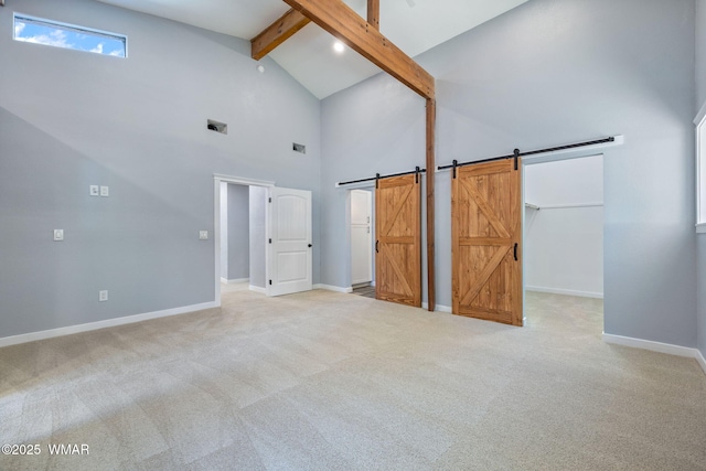 261 S 5th Pl, Show Low, AZ 85901 - unfurnished bedroom featuring a barn door, beamed ceiling, high vaulted ceiling, carpet flooring, and a walk in closet