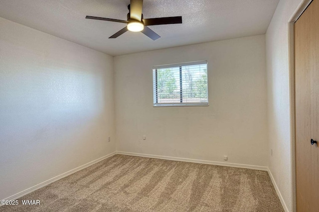 spare room with carpet, baseboards, and a ceiling fan