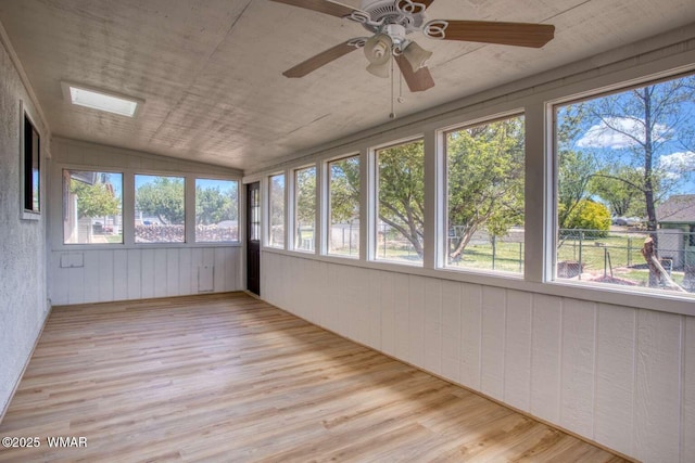 unfurnished sunroom with healthy amount of natural light, wood finished floors, and vaulted ceiling