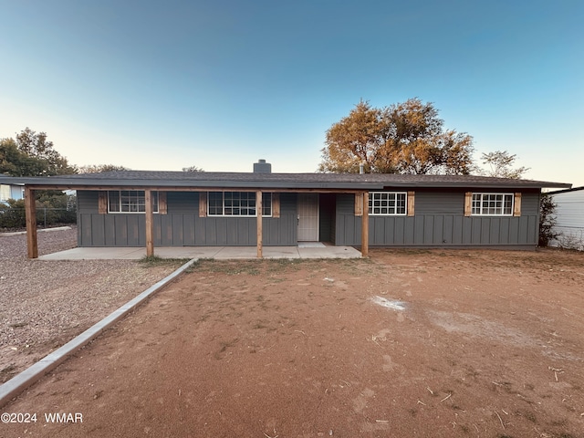 ranch-style house with board and batten siding and a patio