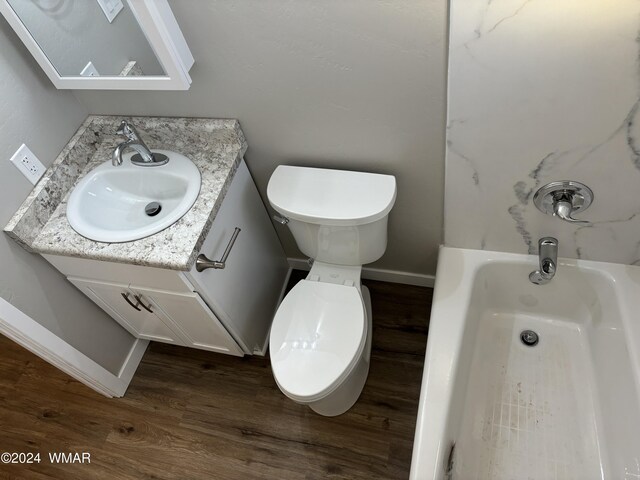 full bathroom featuring toilet, a bathing tub, vanity, wood finished floors, and baseboards