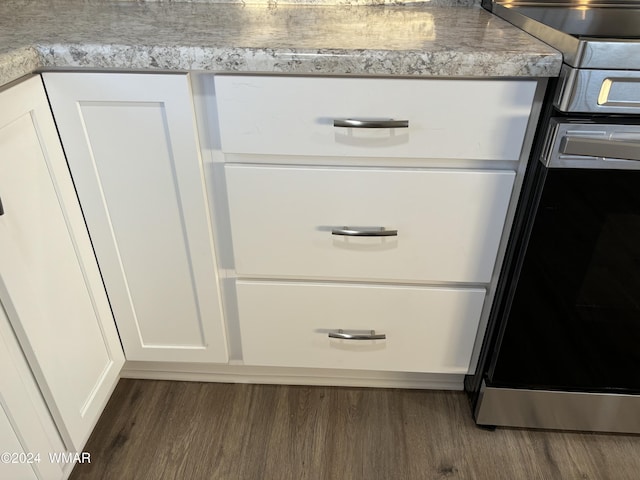 details with stainless steel range oven, light countertops, dark wood-type flooring, and white cabinets