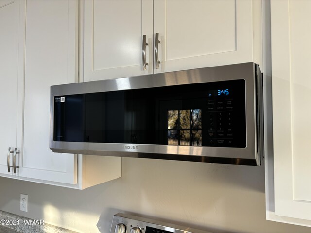 details featuring white cabinets and stainless steel microwave