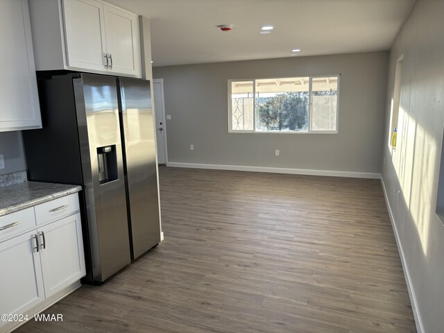 kitchen with white cabinetry, stainless steel refrigerator with ice dispenser, baseboards, and wood finished floors