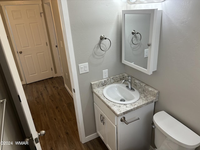 bathroom with baseboards, vanity, toilet, and wood finished floors