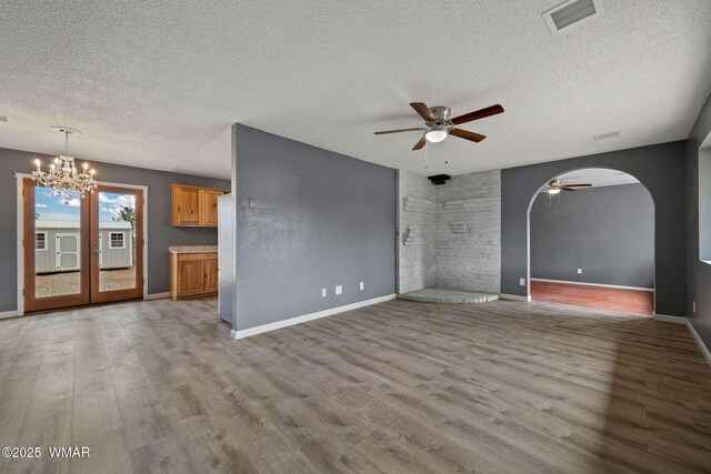 236 E 6th St, Eagar, AZ 85925 - unfurnished living room with ceiling fan, a textured ceiling, arched walkways, wood finished floors, and a chandelier