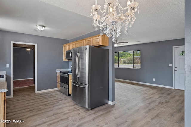 236 E 6th St, Eagar, AZ 85925 - kitchen featuring appliances with stainless steel finishes, light brown cabinets, light wood finished floors, a chandelier, and a textured ceiling