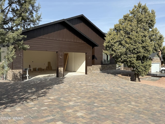 view of front facade with a garage, stone siding, and decorative driveway